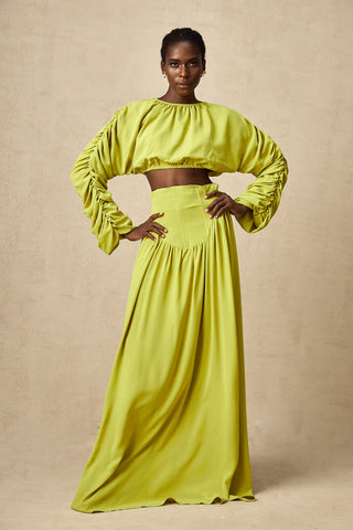 Model wearing a pistachio lime  green smocked long-sleeve crop top paired with a high-waisted pleated maxi skirt, perfect for summer and spring events. Two piece Skirt Set Maxi Long Sleeve - Vienna Shopping Brands to buy things to buy vienna christmas