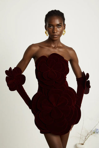 Model wearing a wine-red velvet off-the-shoulder dress with large floral appliqué detailing and matching gloves, creating an elegant and sophisticated look for special occasions. Cielie Vienna Fashion