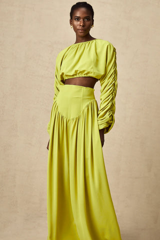 Model wearing a pistachio lime  green smocked long-sleeve crop top paired with a high-waisted pleated maxi skirt, perfect for summer and spring events. Two piece Skirt Set Maxi Long Sleeve - Vienna Shopping Brands to buy things to buy vienna christmas