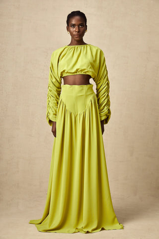 Model wearing a pistachio lime  green smocked long-sleeve crop top paired with a high-waisted pleated maxi skirt, perfect for summer and spring events. Two piece Skirt Set Maxi Long Sleeve - Vienna Shopping Brands to buy things to buy vienna christmas