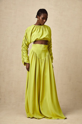 Model wearing a pistachio lime  green smocked long-sleeve crop top paired with a high-waisted pleated maxi skirt, perfect for summer and spring events. Two piece Skirt Set Maxi Long Sleeve - Vienna Shopping Brands to buy things to buy vienna christmas