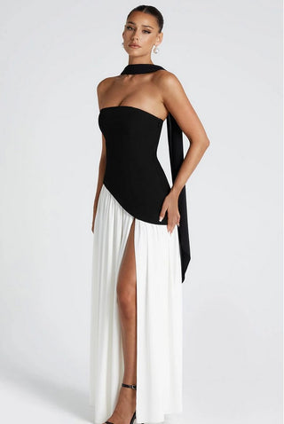 Model wearing strapless black and white maxi dress with sculpted black crepe bodice, asymmetrical hem, white chiffon skirt, high slit, and black chiffon scarf.