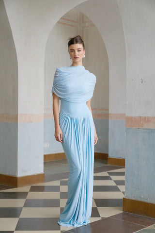 Elegant baby blue asymmetric pleated maxi dress with draped shawl detail, perfect as a wedding guest dress, baby shower dress, or formal evening gown. Sleeveless floor-length blue dress with a figure-flattering fit, ideal for gender reveal parties, spring and summer weddings, and special occasions. Shop this chic and sophisticated pleated maxi dress for a timeless and graceful look.