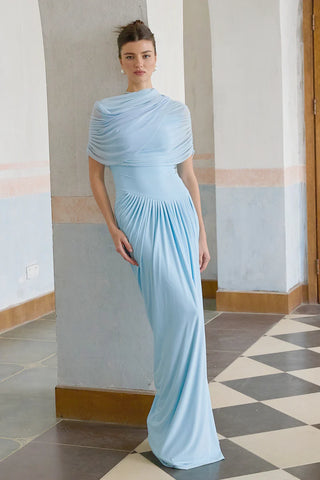 Elegant baby blue asymmetric pleated maxi dress with draped shawl detail, perfect as a wedding guest dress, baby shower dress, or formal evening gown. Sleeveless floor-length blue dress with a figure-flattering fit, ideal for gender reveal parties, spring and summer weddings, and special occasions. Shop this chic and sophisticated pleated maxi dress for a timeless and graceful look.