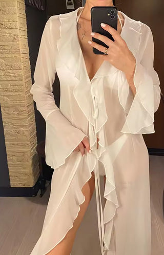 White ruffle mesh beach cover-up with long flared sleeves and front tie closure, styled over a bikini for a boho coastal look by the ocean.
