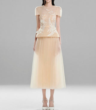 Model wearing beige modest tulle midi skirt and embroidered sheer top set with short sleeves and floral appliqué – elegant outfit for events and modest wear.