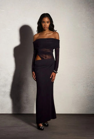 Woman wearing a black off-shoulder dress against a plain background