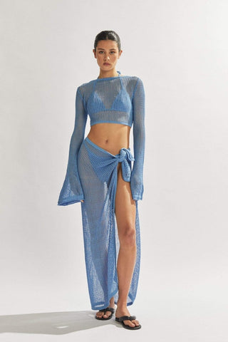 Model in blue crochet crop top with bell sleeves and high-slit midi skirt, styled over swimwear for beach cover-up.