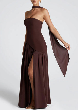 Woman in rich brown maxi dress with scarf at formal outdoor wedding setting, styled with nude heels.