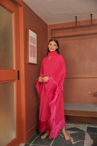 Woman in a bright pink dress standing in a room with a red wall and door.