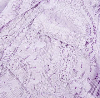 Woman wearing a lavender lace two-piece summer set with short-sleeve buttoned top and floral embroidered flared skirt, perfect for vacation or coastal getaway.