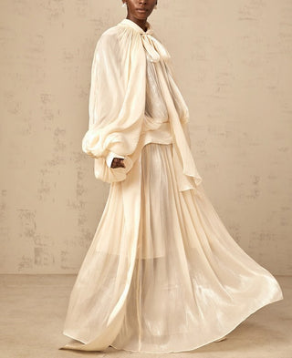 Elegant ivory satin gown styled for modern modest bride – long sleeve wedding maxi dress with flowing silhouette.