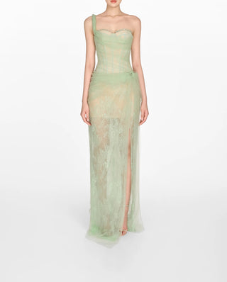 Model wearing a soft green tulle lace dress with asymmetrical one-shoulder strap, fitted bodice, and draped skirt, perfect for summer weddings and special occasions.