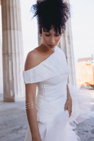 White pant suit set bridal - Asymmetric off-shoulder top with entire gathering detail and fitted waist, paired with wide-leg pleated pants. Perfect for modern brides, business attire, and summer events. Elegant and sophisticated design ideal for versatile occasions.