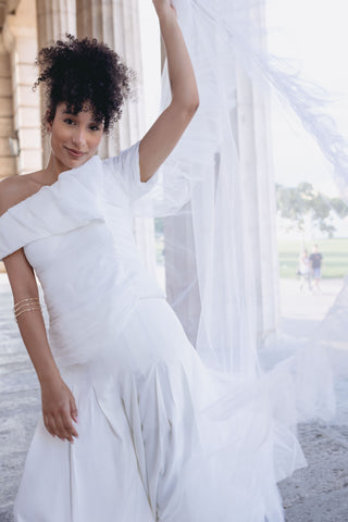 White pant suit set bridal - Asymmetric off-shoulder top with entire gathering detail and fitted waist, paired with wide-leg pleated pants. Perfect for modern brides, business attire, and summer events. Elegant and sophisticated design ideal for versatile occasions.