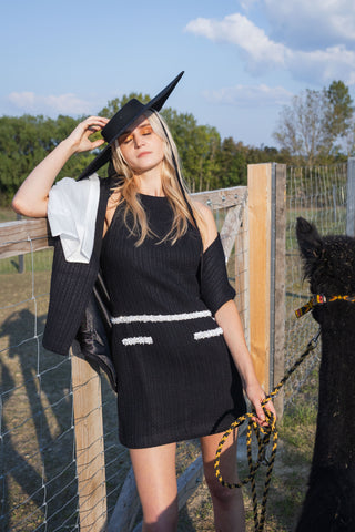 Model wearing a black and white beaded knit cape from the Desole Collection AW24 by Cielie, featuring a detachable satin bow and semi-fitted silhouette. This elegant monochrome cape coat is perfect for formal events or casual chic outfits, designed for cooler weather.