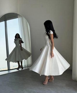 Model wearing white satin midi dress with cap sleeves for wedding shower