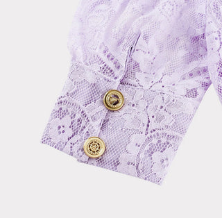 Woman wearing a lavender lace two-piece summer set with short-sleeve buttoned top and floral embroidered flared skirt, perfect for vacation or coastal getaway.