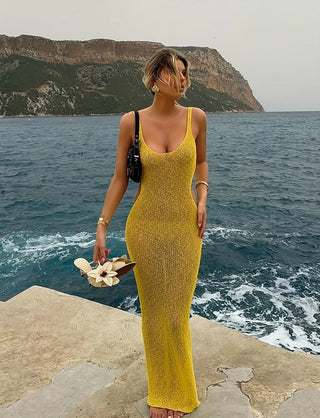 Woman wearing a yellow crochet maxi beach dress with side cut-outs, posing with arm raised, showcasing the dress’s fit and texture.