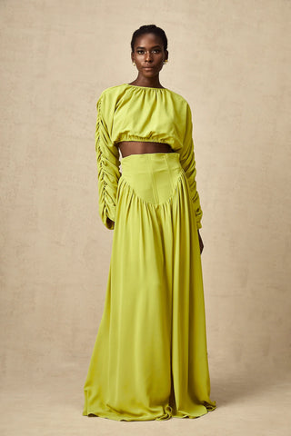 Model wearing a pistachio lime  green smocked long-sleeve crop top paired with a high-waisted pleated maxi skirt, perfect for summer and spring events. Two piece Skirt Set Maxi Long Sleeve - Vienna Shopping Brands to buy things to buy vienna christmas 