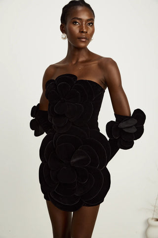 Model wearing a black velvet off-the-shoulder dress with large floral appliqué detailing and matching gloves, perfect for holiday parties, Christmas, and New Year's celebrations.