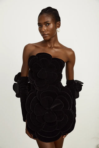 Model wearing a black velvet off-the-shoulder dress with large floral appliqué detailing and matching gloves, perfect for holiday parties, Christmas, and New Year's celebrations.