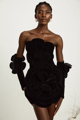 Model wearing a black velvet off-the-shoulder dress with large floral appliqué detailing and matching gloves, perfect for holiday parties, Christmas, and New Year's celebrations.