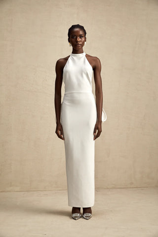 A sophisticated model wearing the Serinay White Oversize-Bow Bandage Dress, featuring a sleek sleeveless design, a round neckline, and an oversized bow detail at the back. The maxi-length dress includes an open back, a rear slit, and a sculpting bandage fit, perfect for bridal events, engagement parties, and wedding rehearsals.