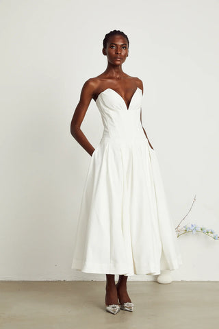 Elegant strapless white midi dress with corset-style bodice and pleated skirt, a chic House of CB dupe. Perfect as a minimalist bridal dress, with vintage-inspired elegance for weddings and formal events.