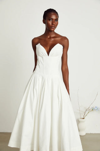 Elegant strapless white midi dress with corset-style bodice and pleated skirt, a chic House of CB dupe. Perfect as a minimalist bridal dress, with vintage-inspired elegance for weddings and formal events.