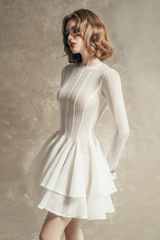 White crochet long sleeve mini dress with lace trim and ruffled double-layered skirt.