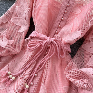 Close-up of a pink lace garment with intricate details and buttons.