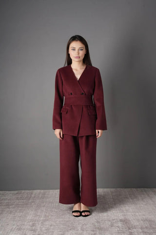 Model wearing the burgundy wool blazer and pants set, styled for a chic professional look with a black chain strap bag.