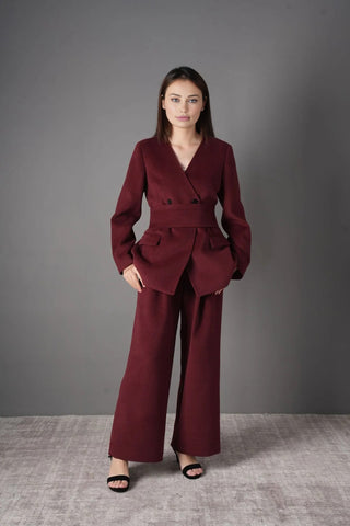 Model wearing the burgundy wool blazer and pants set, styled for a chic professional look with a black chain strap bag.