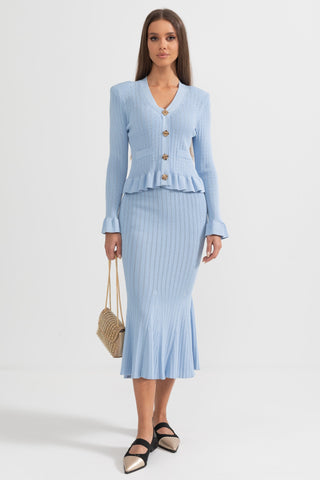 Woman wearing a light blue cardigan and skirt set on a white background