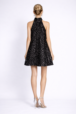 Black sequin dress worn by a model on a white background