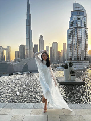Woman in a white dress standing on a rooftop with a city skyline in the background