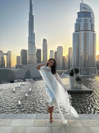 Woman in a white dress standing on a rooftop with a city skyline in the background