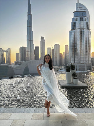 Woman in a white dress standing on a rooftop with a city skyline in the background