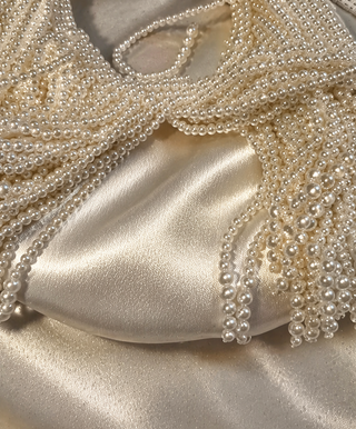 Close-up of a beaded clutch bag with pearl detailing on a satin surface