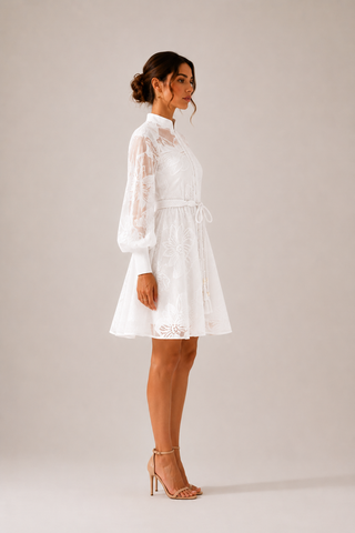 White floral lace mini dress featuring intricate embroidered lace, sheer long sleeves, high neckline, detachable braided waist belt, coordinating slip dress, fit and flare silhouette, and concealed back zipper closure, perfect for bridal showers, engagement parties, courthouse weddings, white parties, graduations, vacations, and elegant summer occasions.