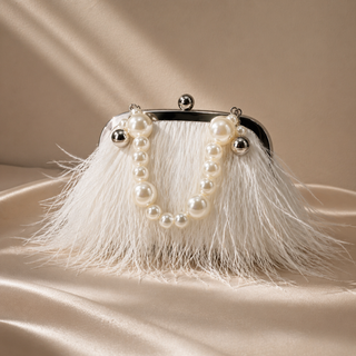 Handbag with pearl embellishments and white feathers on a beige background
