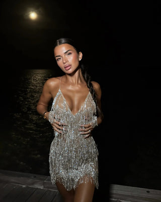 Woman wearing a silver beaded dress against a dark background