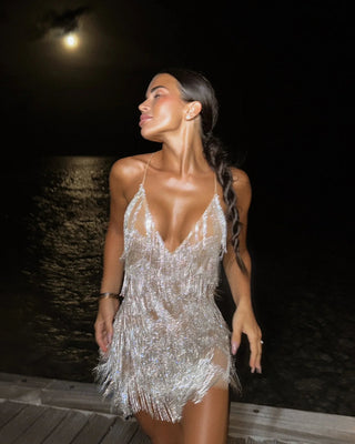 Woman in a sparkly dress standing outdoors at night.