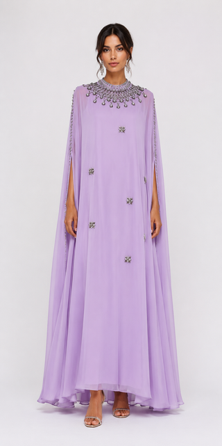A model wearing a lavender purple caftan dress with silver embellishments on the collar and scattered across the front, set against a plain light gray background.