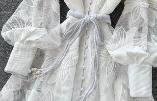 White lace dress with a bow detail on a textured surface