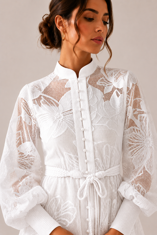White floral lace mini dress featuring intricate embroidered lace, sheer long sleeves, high neckline, detachable braided waist belt, coordinating slip dress, fit and flare silhouette, and concealed back zipper closure, perfect for bridal showers, engagement parties, courthouse weddings, white parties, graduations, vacations, and elegant summer occasions.