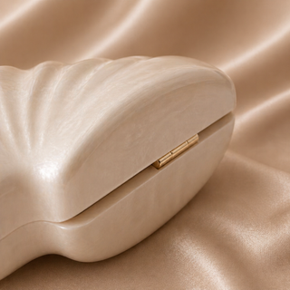 Beige clutch bag with gold clasp on a beige fabric background