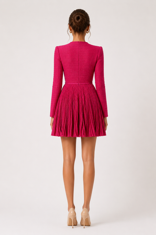 Person wearing a bright pink dress with pleated skirt on a white background