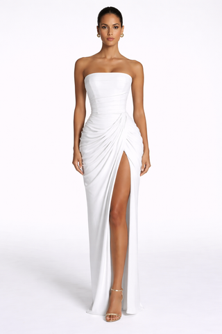 Woman wearing a white strapless gown with a high slit on a white background